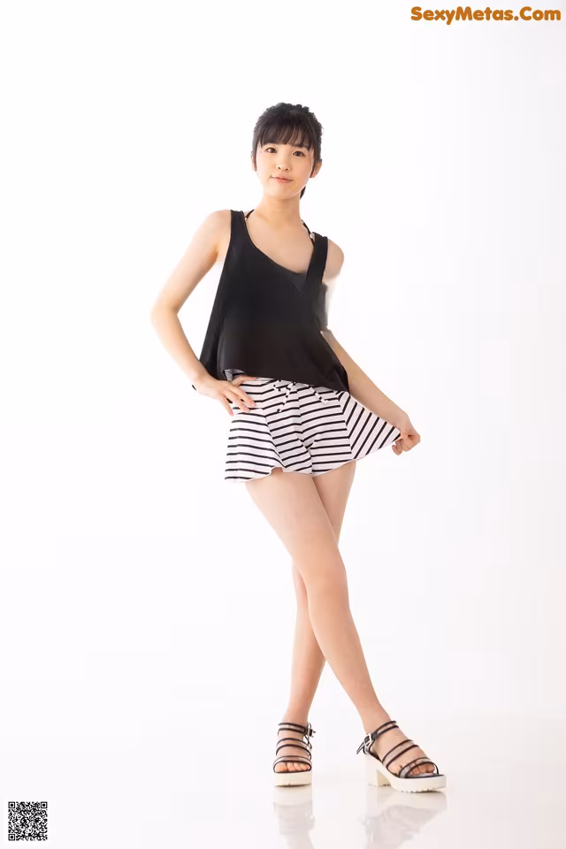 A woman in a black tank top and striped shorts posing for a picture.