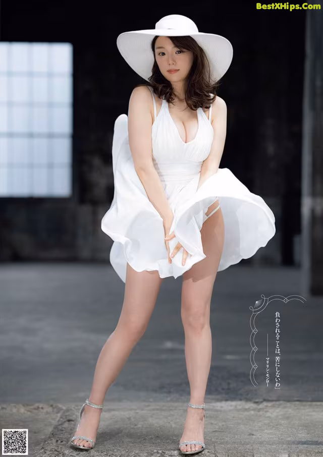A woman in a white dress and hat posing for a picture.
