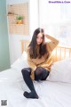 A woman sitting on a bed wearing black tights.