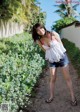 A woman in a white top and denim shorts posing for a picture.