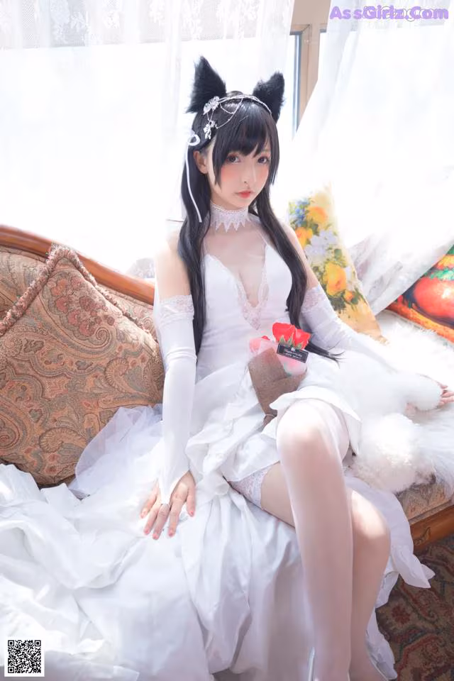 A woman in a white dress sitting on a couch.