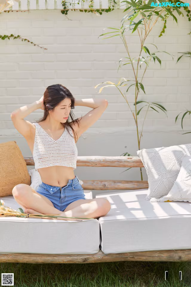 A woman sitting on a white couch in the grass.