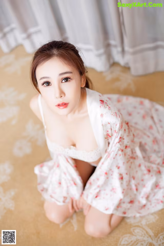 A woman in a white dress sitting on the floor.