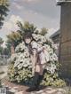 A girl in a school uniform standing in front of a bush of flowers.