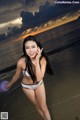 A woman in a white bikini standing on a beach.