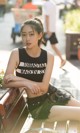 A woman sitting on top of a wooden bench.