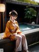 A woman in a yellow kimono sitting by a pool.