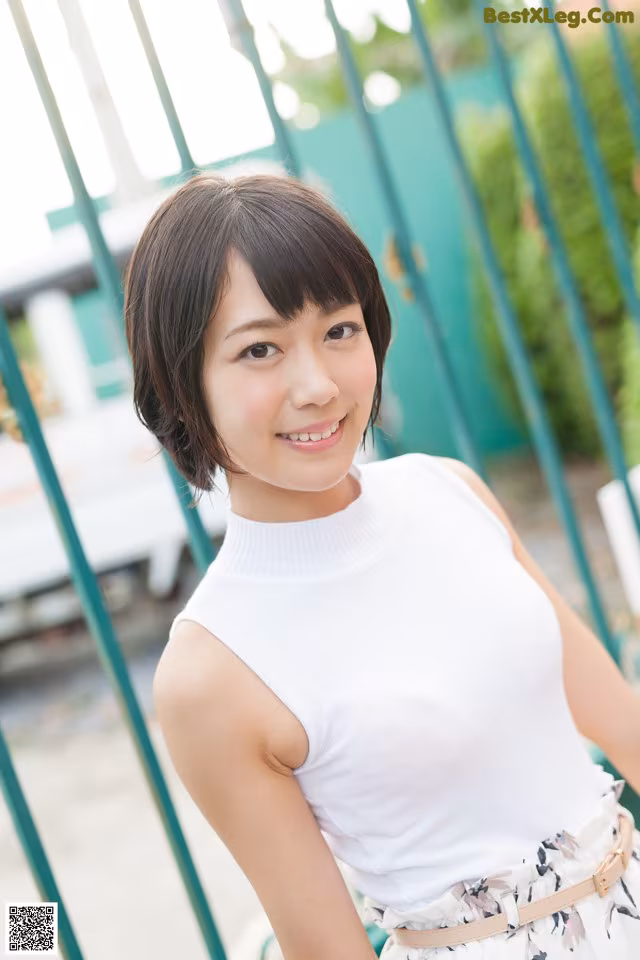 A woman in a white top and floral skirt posing for a picture.