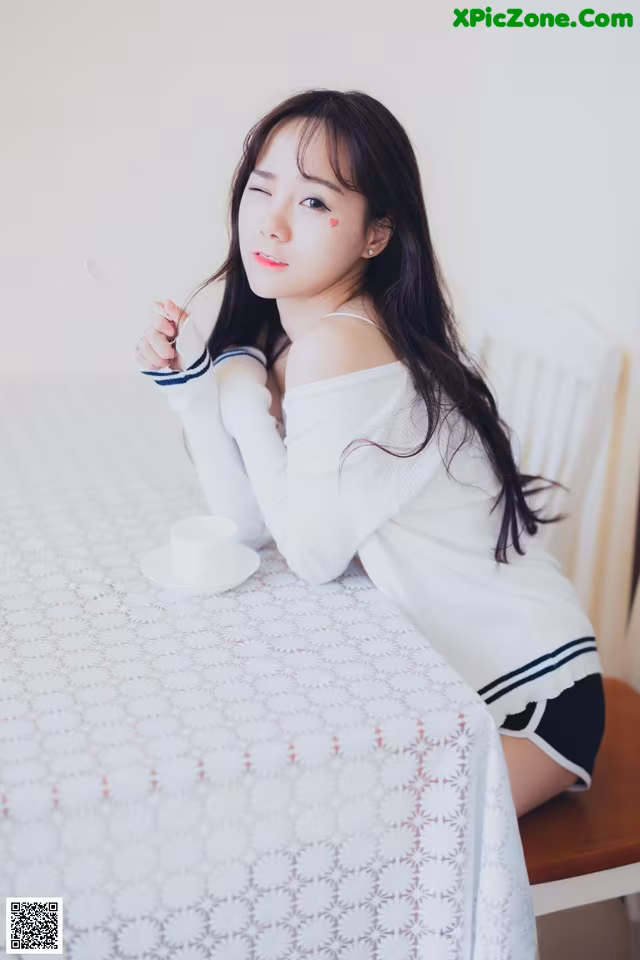 A woman sitting at a table with a cup of coffee.