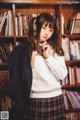 A young woman standing in front of a bookshelf.