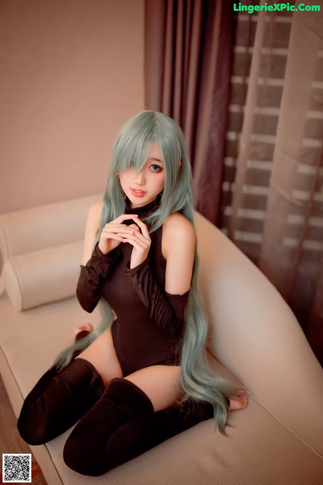 A woman with long green hair sitting on a couch.
