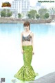 A woman in a mermaid costume standing by a pool.