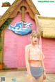 A woman in a bikini standing in front of a pink building.