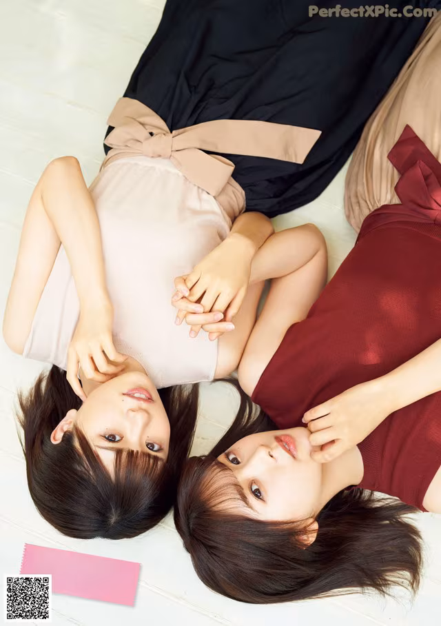A couple of women laying on top of a wooden floor.