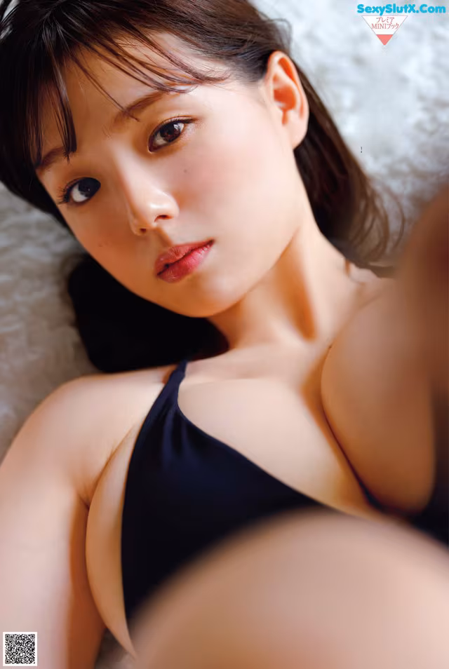 A woman in a black bikini laying on a bed.