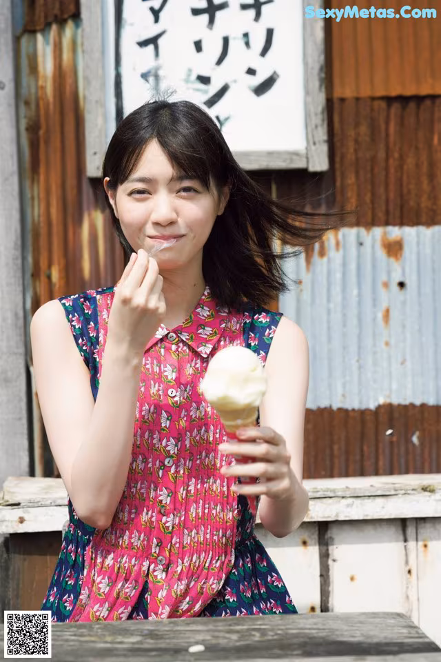 A woman eating an ice cream cone in front of a building.