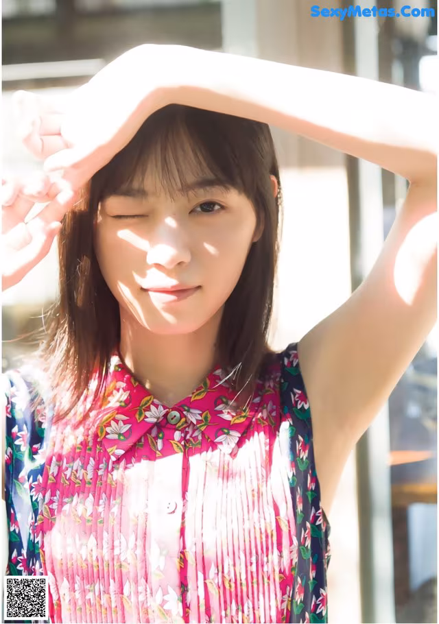 A woman in a pink dress is posing for a picture.