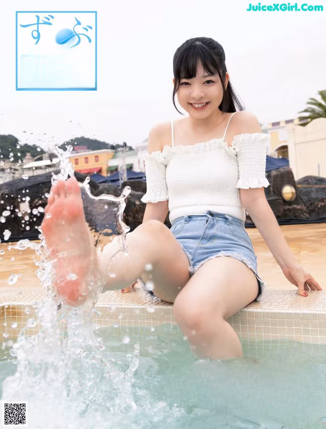 A woman sitting on the edge of a swimming pool with her feet in the water.