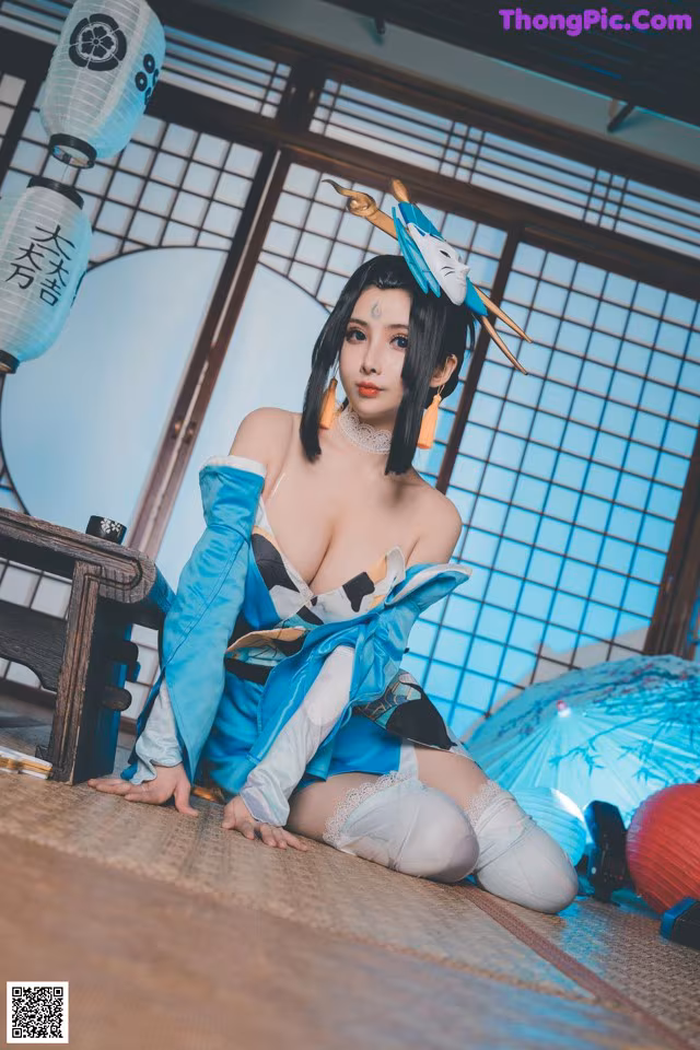 A woman in a blue and white outfit sitting on the floor.