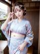 A woman in a blue kimono posing for a picture.