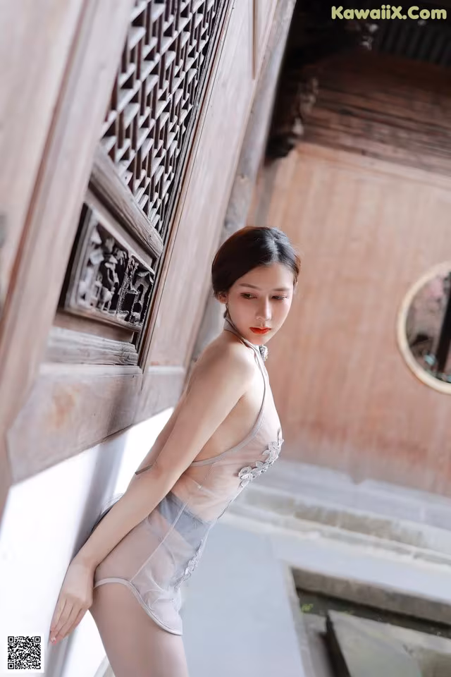 A woman in a white lingerie leaning against a wall.