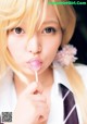 A woman in a school uniform holding a lollipop in her mouth.