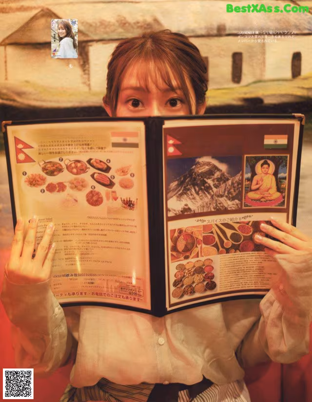 A woman holding up a menu in front of her face.