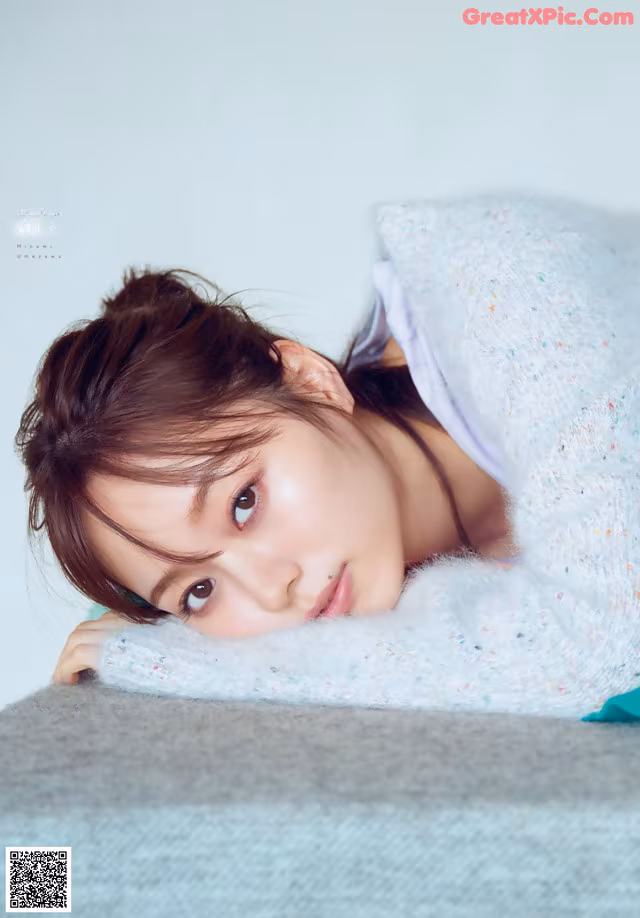 A young woman laying on top of a bed under a blanket.