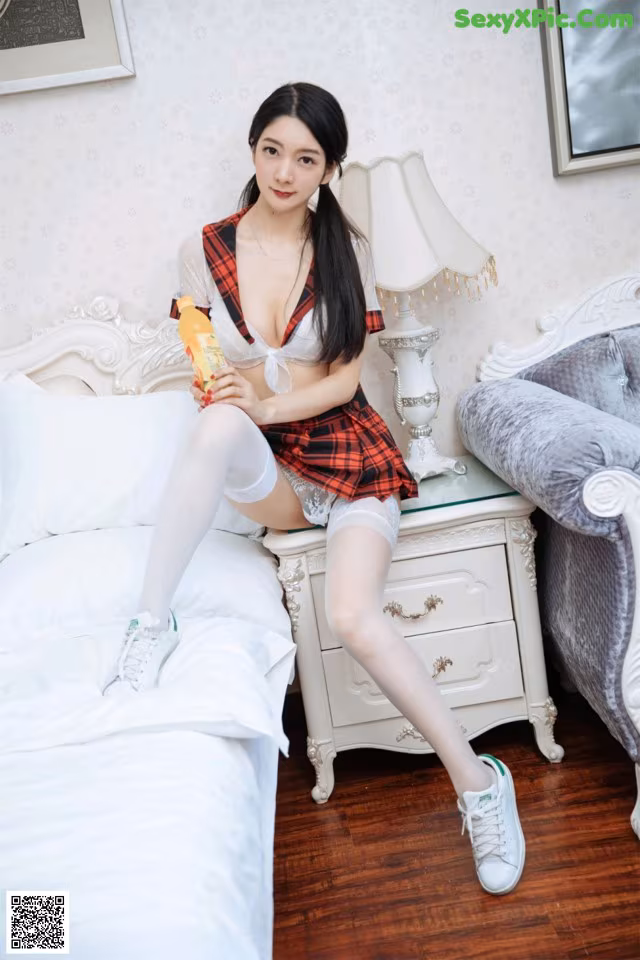 A woman sitting on top of a bed holding a bottle of orange juice.