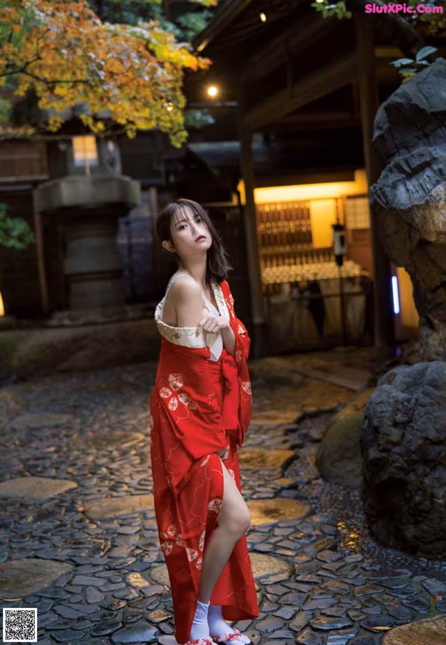 A woman in a red kimono standing in front of a building.